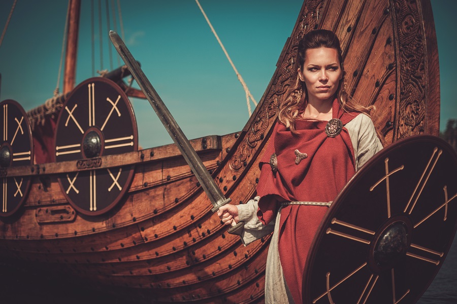 Viking woman wearing traditional clothes near a ship